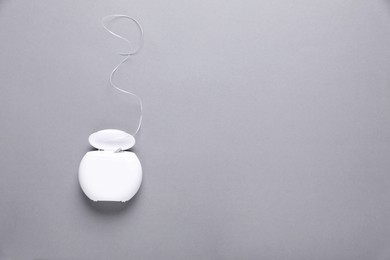 Photo of Container with dental floss on grey background, top view. Space for text