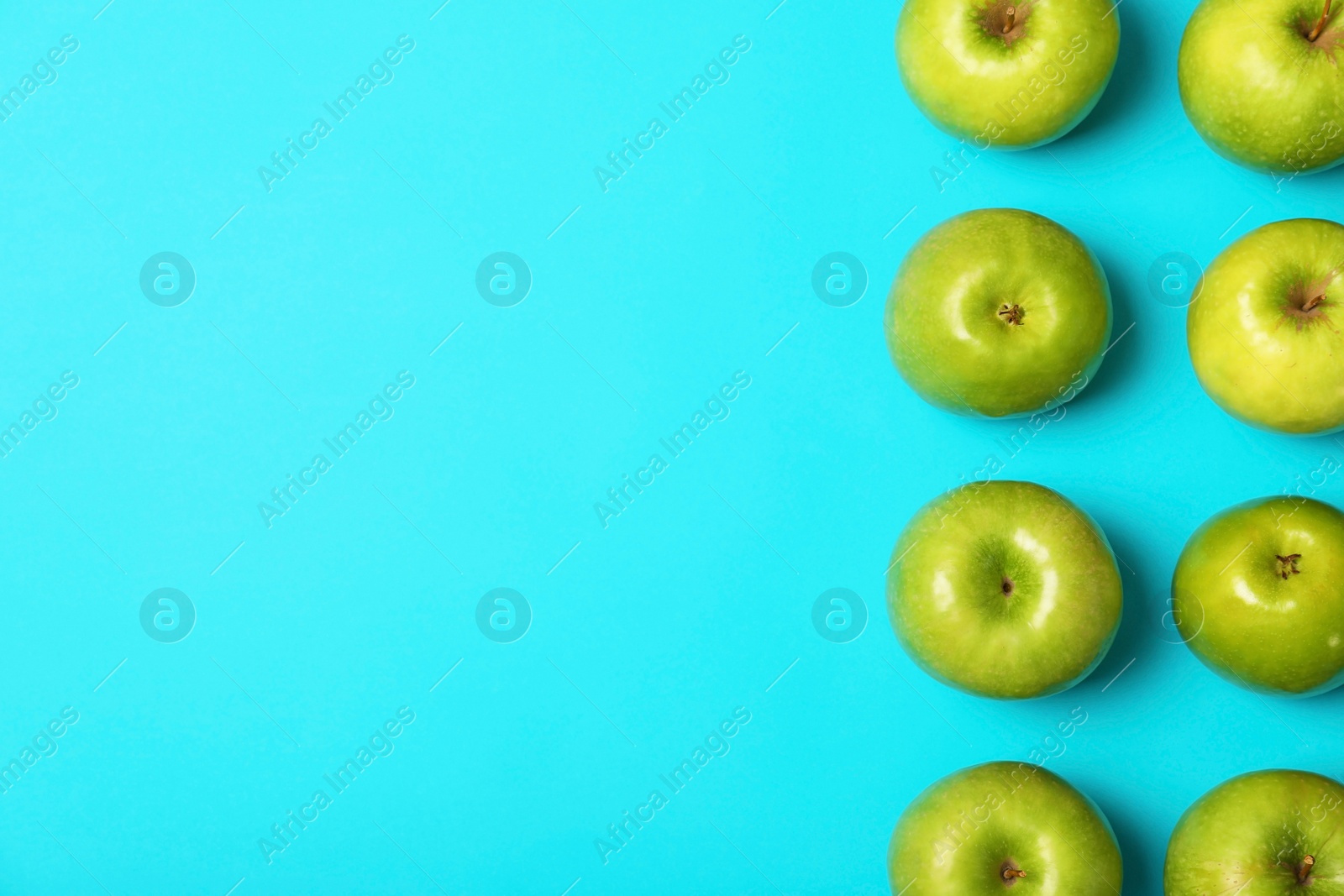 Photo of Many juicy green apples and space for text on color background, top view