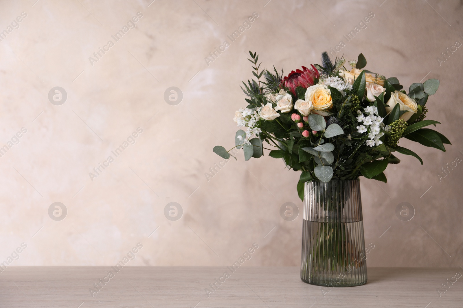 Photo of Beautiful bouquet with roses on wooden table. Space for text