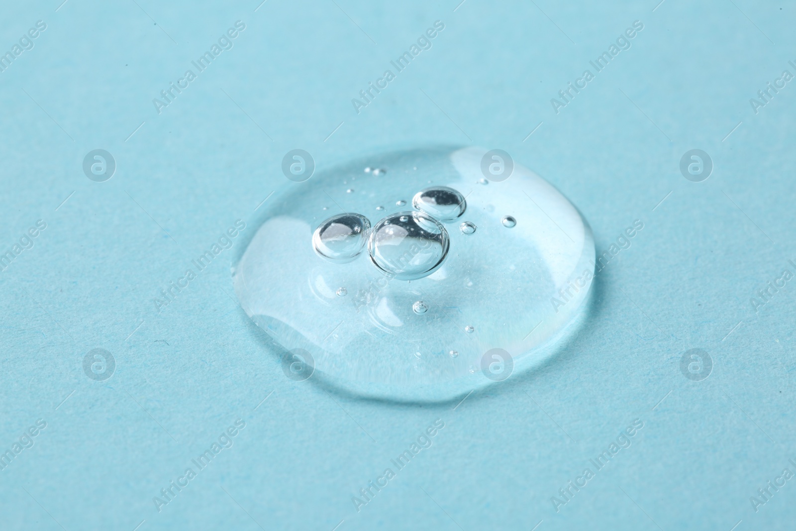 Photo of Drop of cosmetic serum on light blue background, closeup