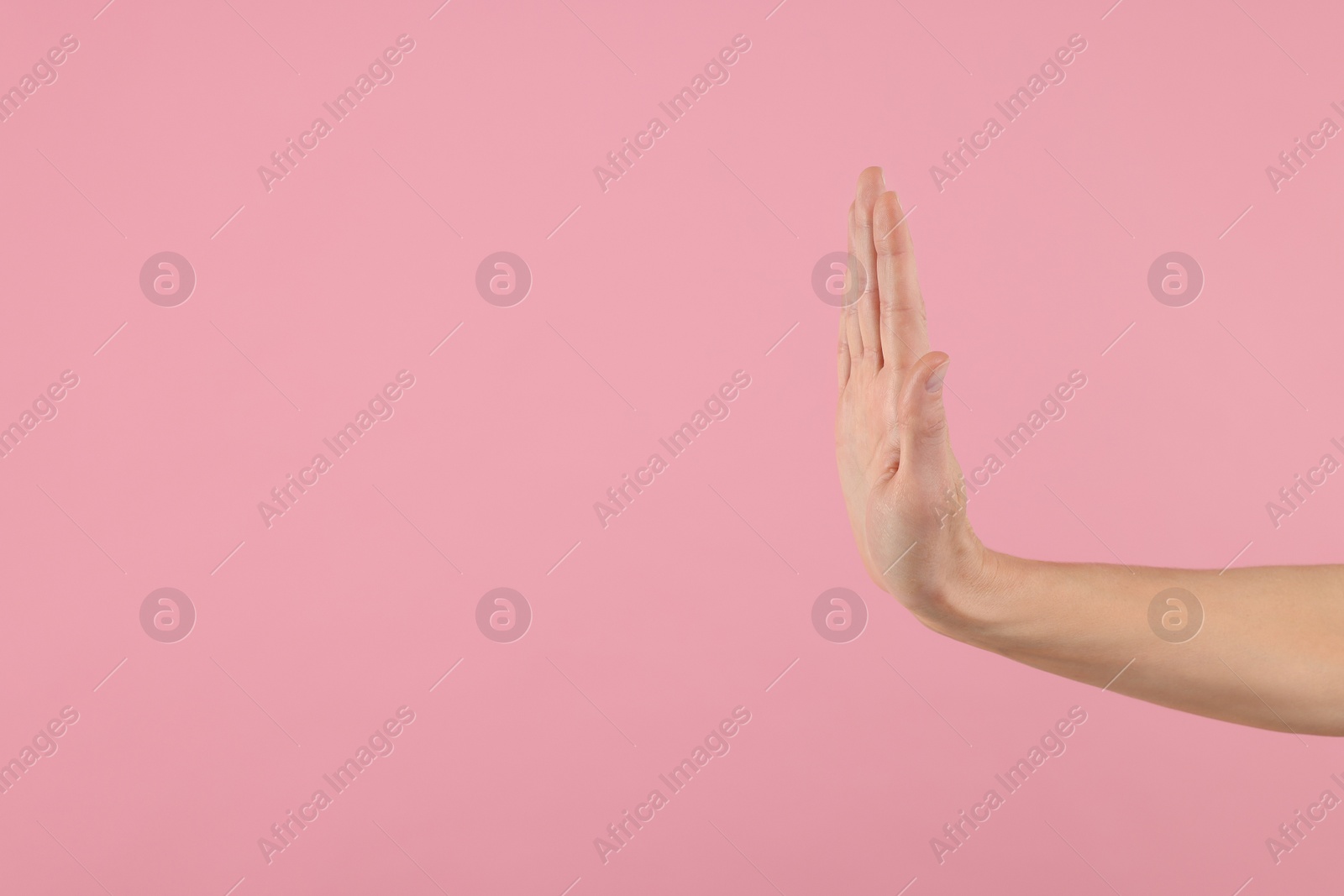 Photo of Woman showing stop gesture on pink background, closeup. Space for text