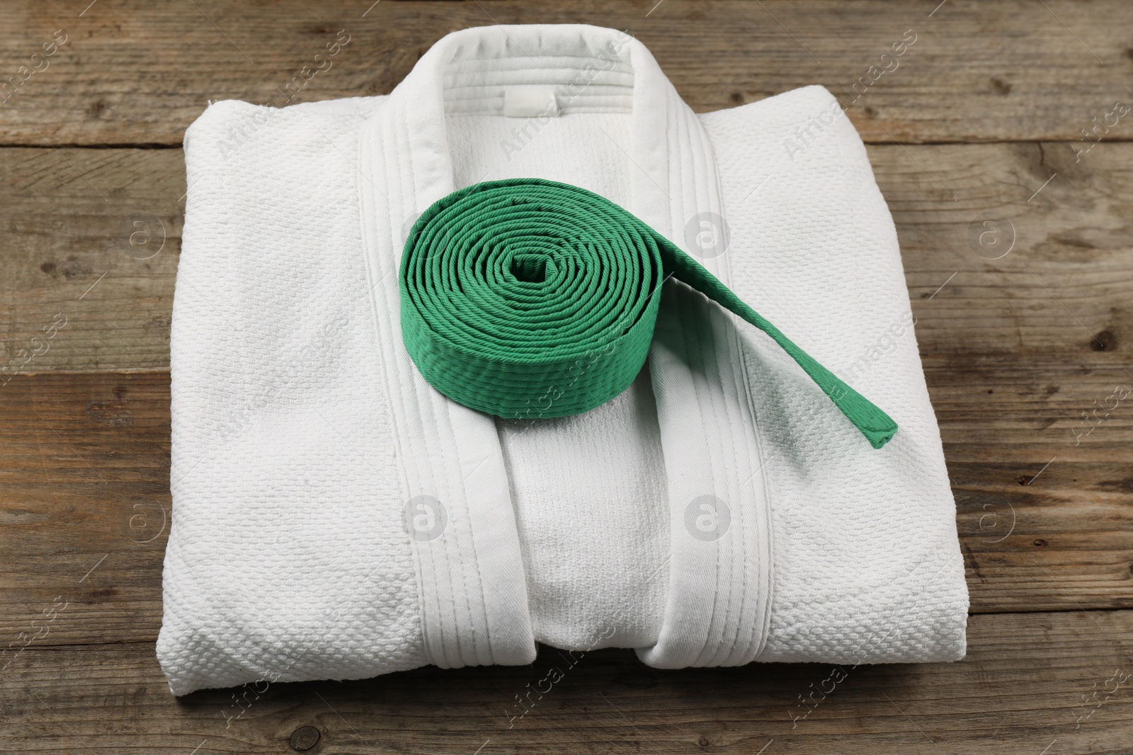 Photo of Green karate belt and white kimono on wooden background