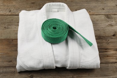 Photo of Green karate belt and white kimono on wooden background