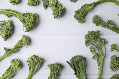 Photo of Frame made of fresh raw broccolini on white table, flat lay and space for text. Healthy food