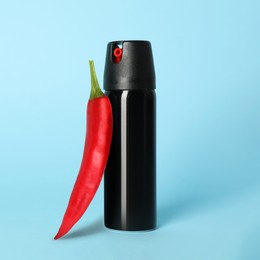 Bottle of pepper spray and red hot chilli on turquoise background