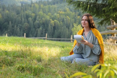 Photo of Beautiful young woman drawing with pencil in notepad on green grass