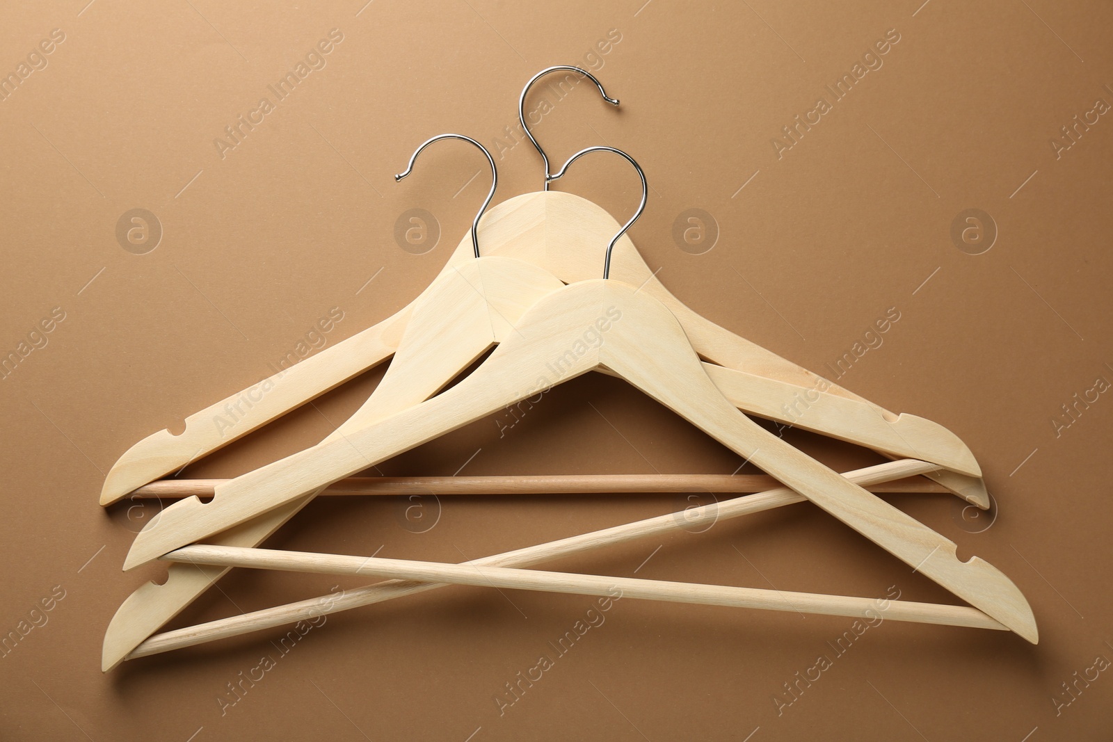 Photo of Wooden hangers on brown background, top view