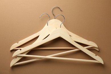 Photo of Wooden hangers on brown background, top view