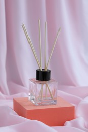 Stylish presentation of reed diffuser on pink fabric
