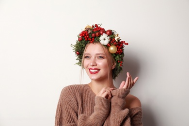 Photo of Beautiful young woman wearing Christmas wreath on white background