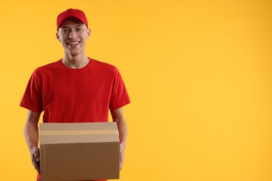 Photo of Happy courier with parcel on yellow background. Space for text