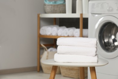 Photo of Folded soft terry towels on white table in bathroom, space for text