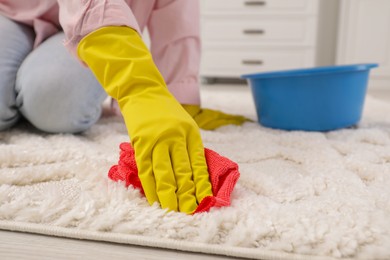 Photo of Woman in rubber gloves cleaning carpet with rag indoors, closeup. Space for text