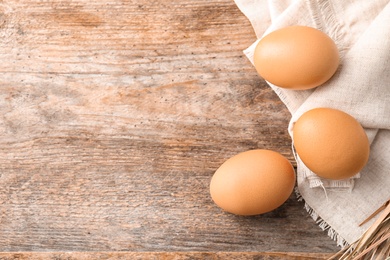 Photo of Raw chicken eggs on wooden background, top view. Space for text