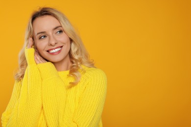 Photo of Happy woman in stylish warm sweater on orange background. Space for text