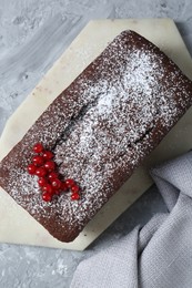 Tasty chocolate sponge cake with powdered sugar and currant on light grey textured table, top view