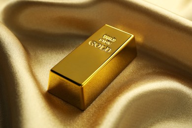 Gold bar on shiny silk fabric, closeup