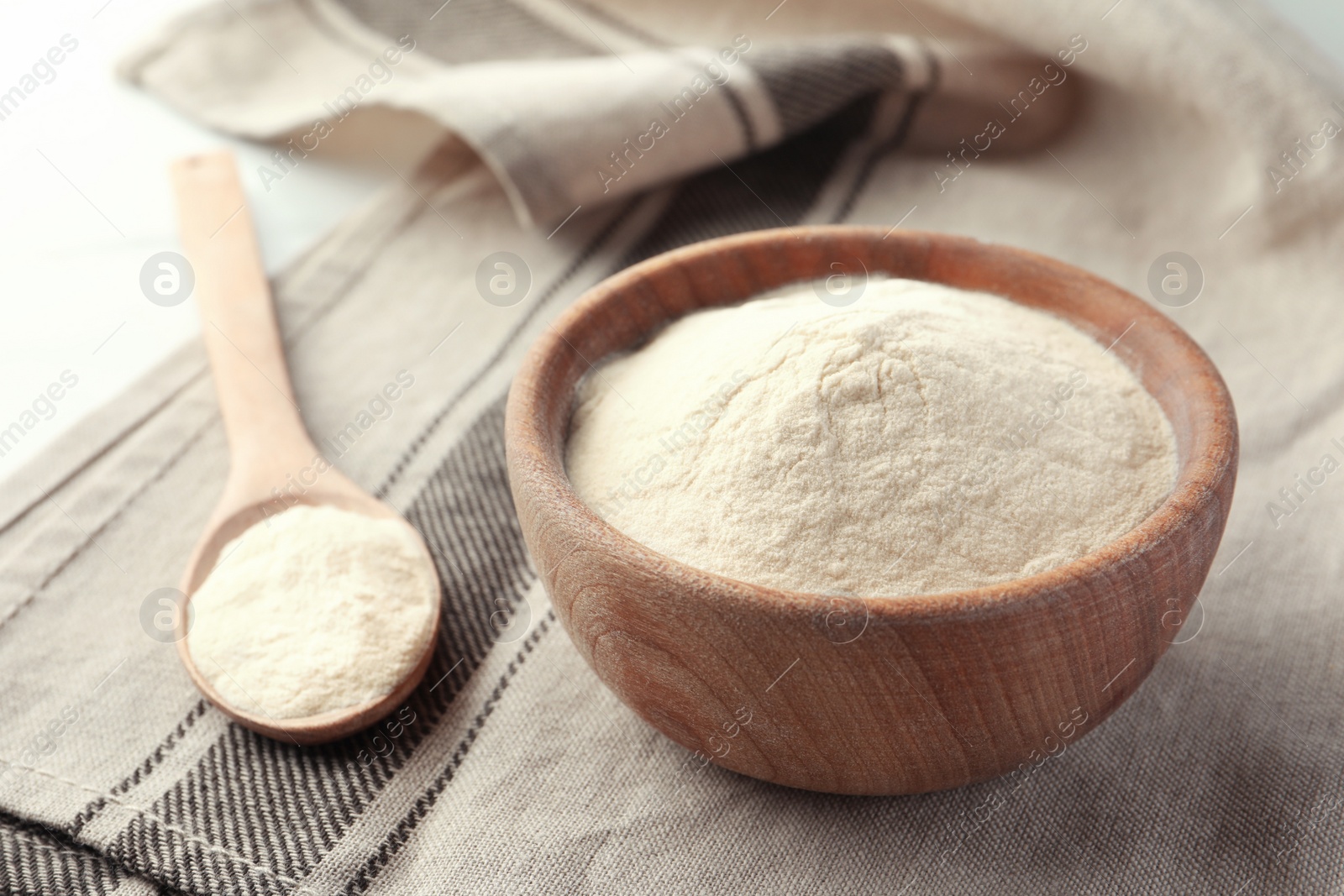 Photo of Bowl and spoon with agar-agar powder on cloth, closeup