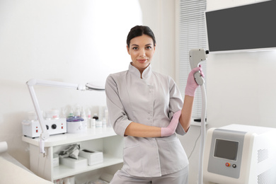 Young woman holding professional laser epilator in beauty salon