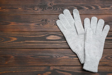 Pair of stylish woolen gloves on wooden background, flat lay. Space for text