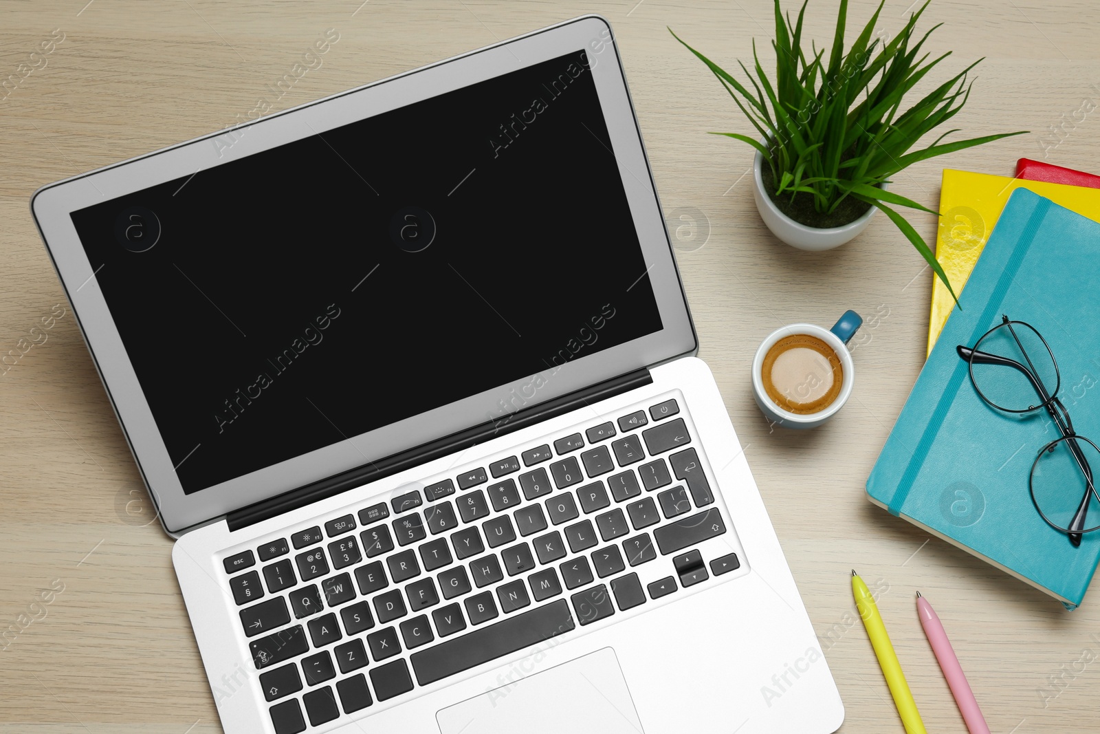 Photo of Modern laptop, cup of coffee and office stationery on wooden table, flat lay. Distance learning