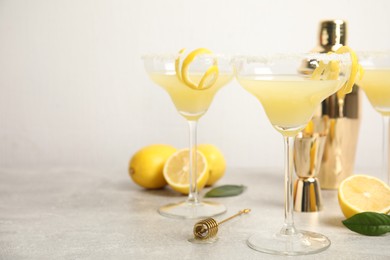 Photo of Delicious bee's knees cocktails and ingredients on light grey table, space for text