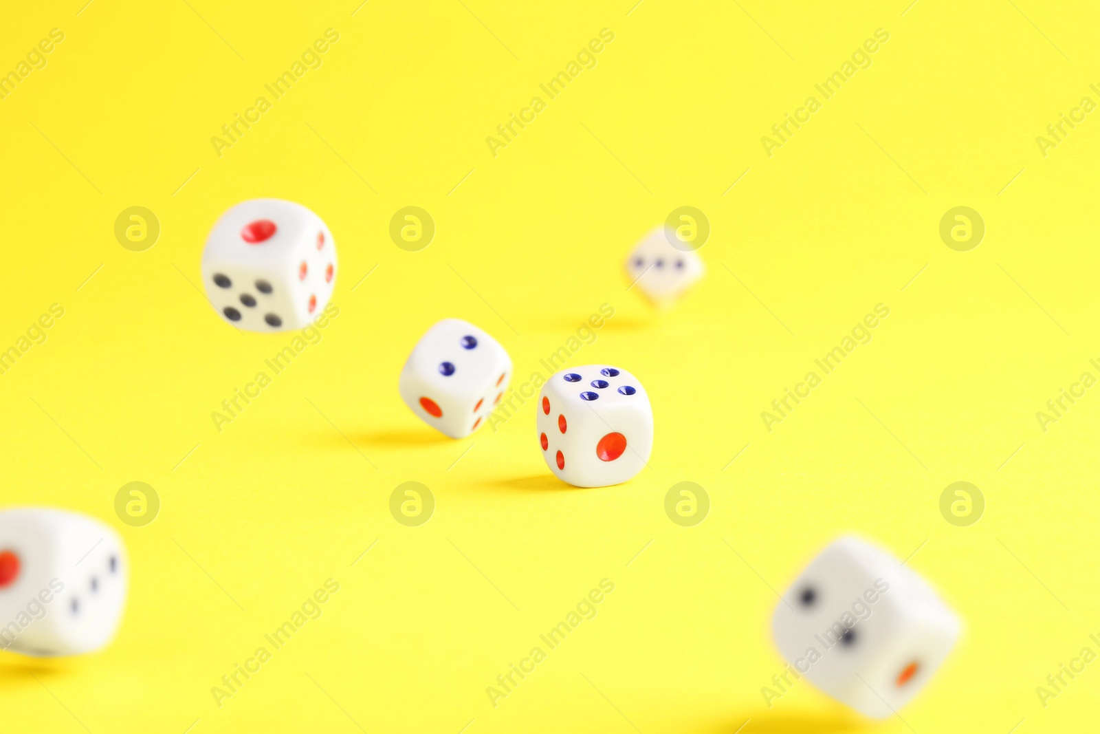 Photo of Many white game dices falling on yellow background. Space for text