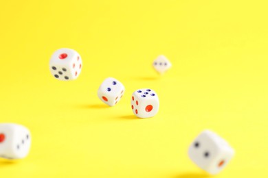 Photo of Many white game dices falling on yellow background. Space for text