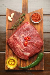 Photo of Fresh raw beef cut, spices and oil on wooden table, top view