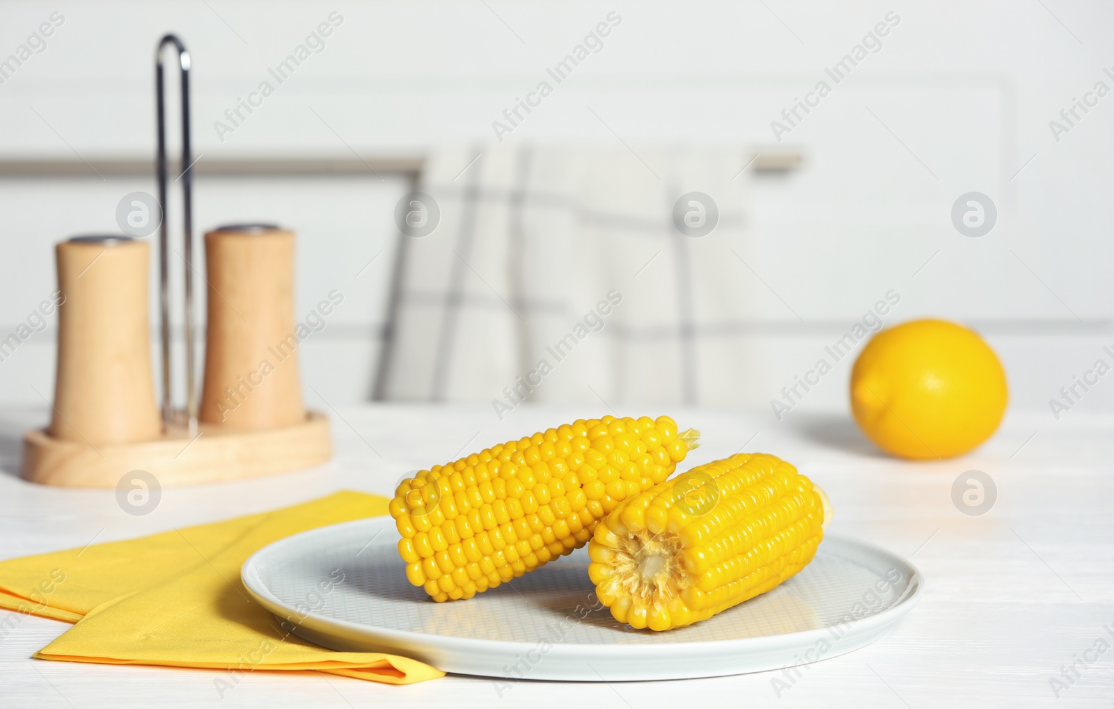 Photo of Plate with ripe corn cobs on table