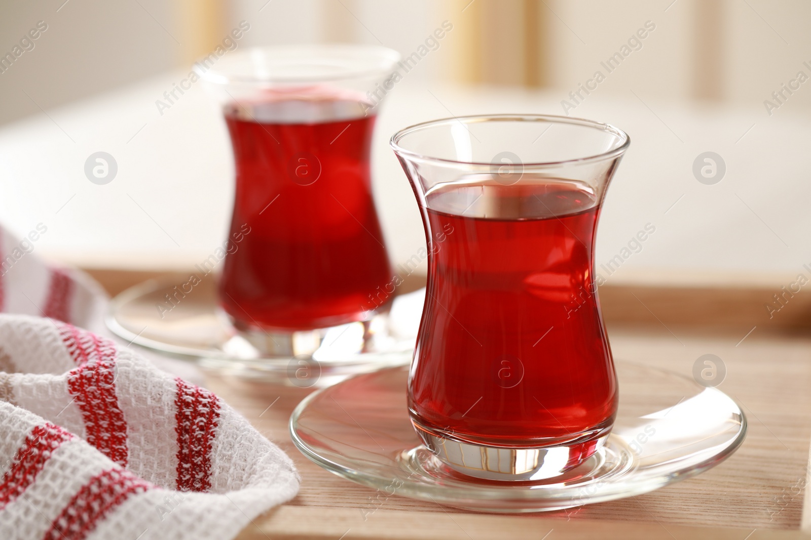 Photo of Glasses of traditional Turkish tea on wooden tray, closeup