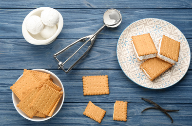 Photo of Sweet delicious ice cream cookie sandwiches served on blue wooden table, flat lay