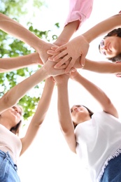 Photo of Happy women putting hands together outdoors, bottom view. Girl power concept