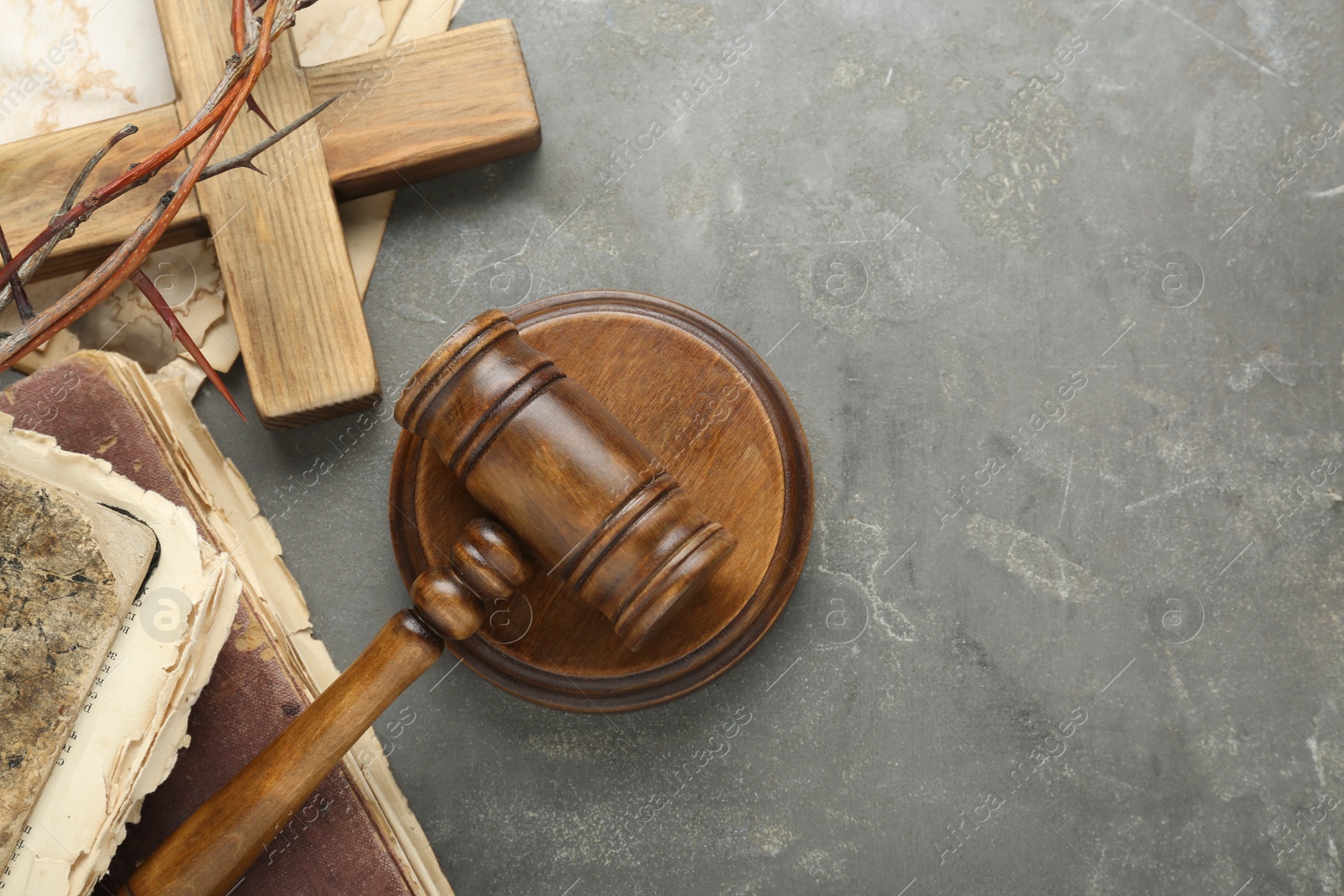 Photo of Judge gavel, old books and wooden cross on grey table, flat lay. Space for text