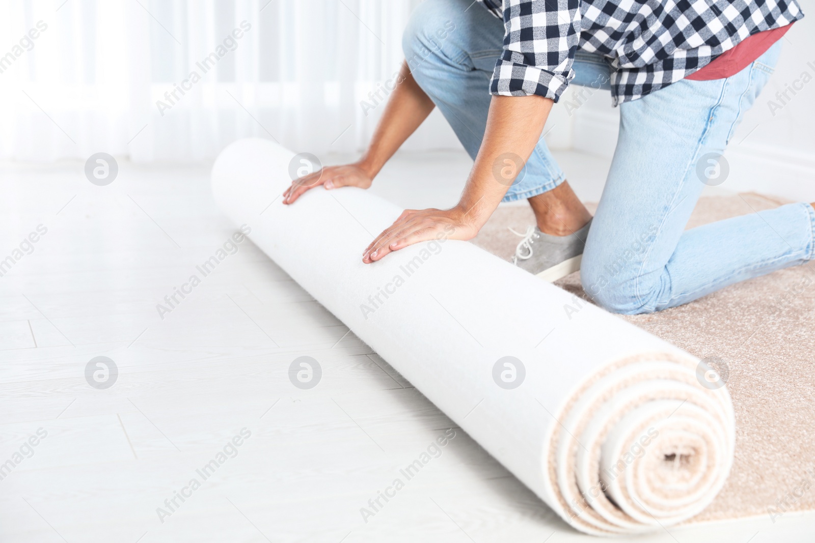 Photo of Man rolling out new carpet flooring indoors, closeup. Space for text