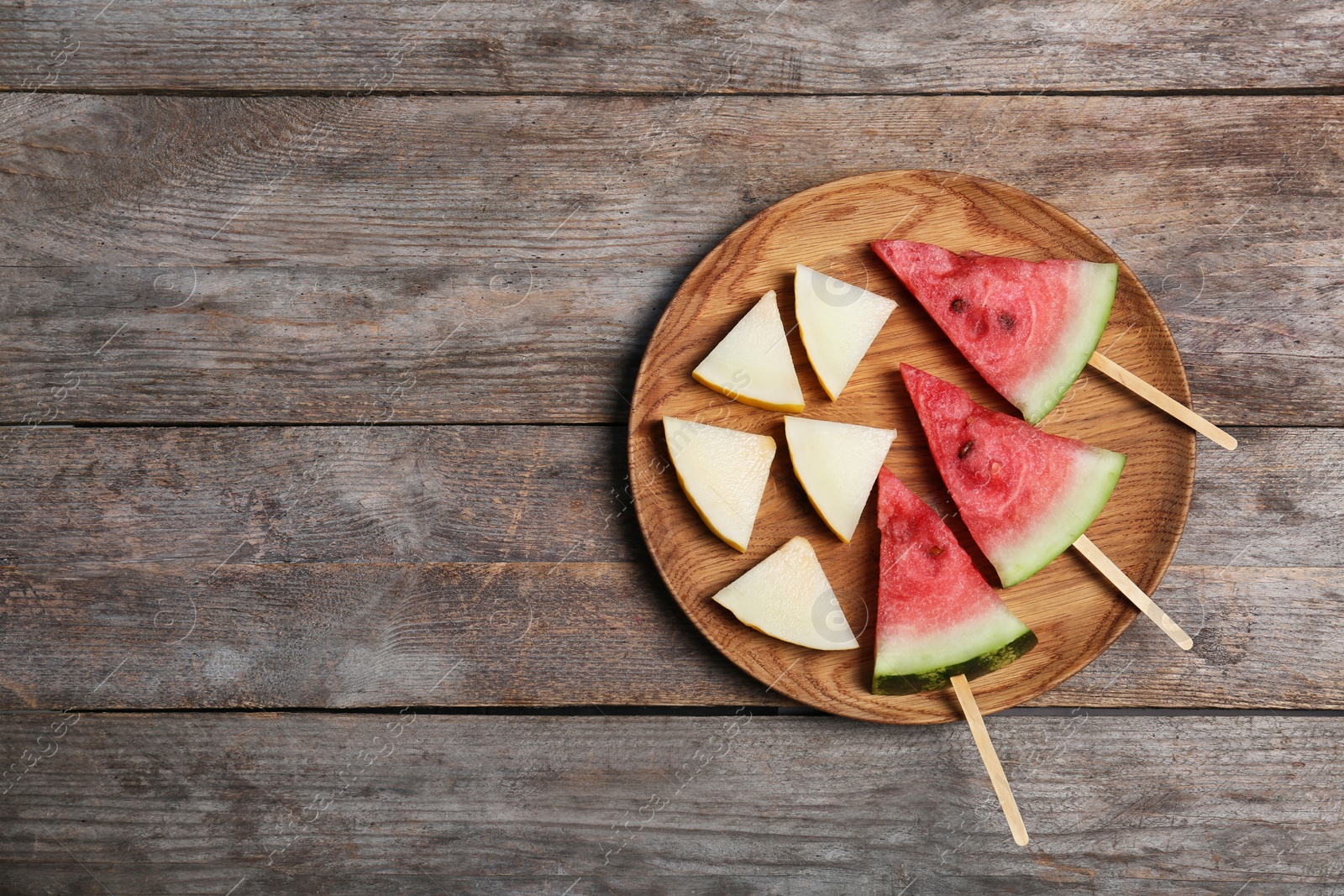 Photo of Watermelon and melon slices on wooden background, flat lay. Space for text