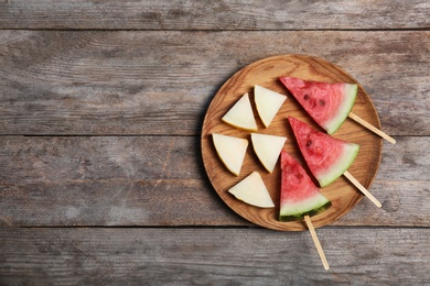 Watermelon and melon slices on wooden background, flat lay. Space for text