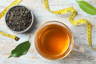 Photo of Flat lay composition with herbal diet tea and measuring tape on wooden table. Weight loss concept