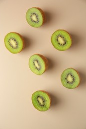 Photo of Halves of fresh kiwis on beige background, flat lay