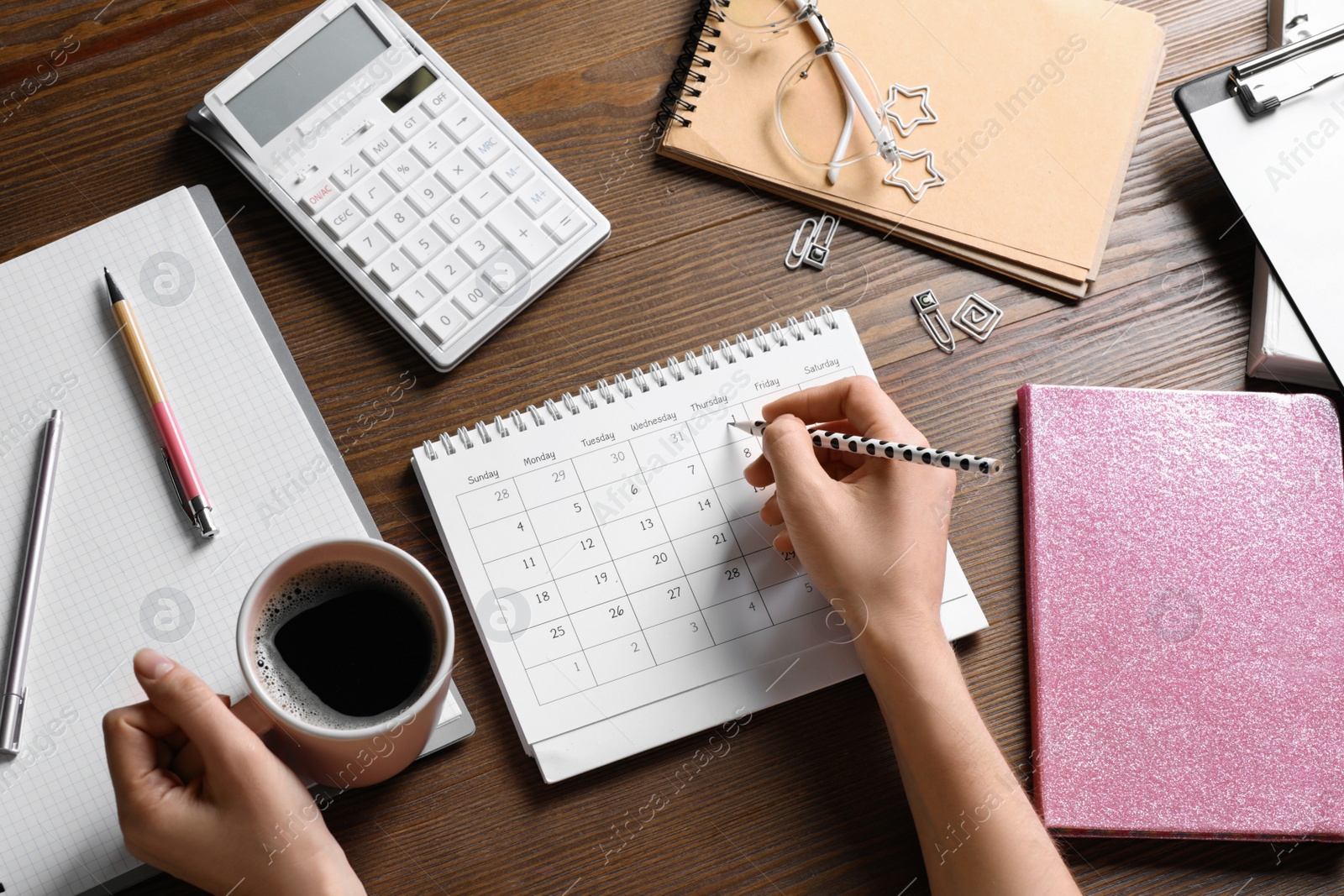 Photo of Woman marking date in calendar at wooden table, top view