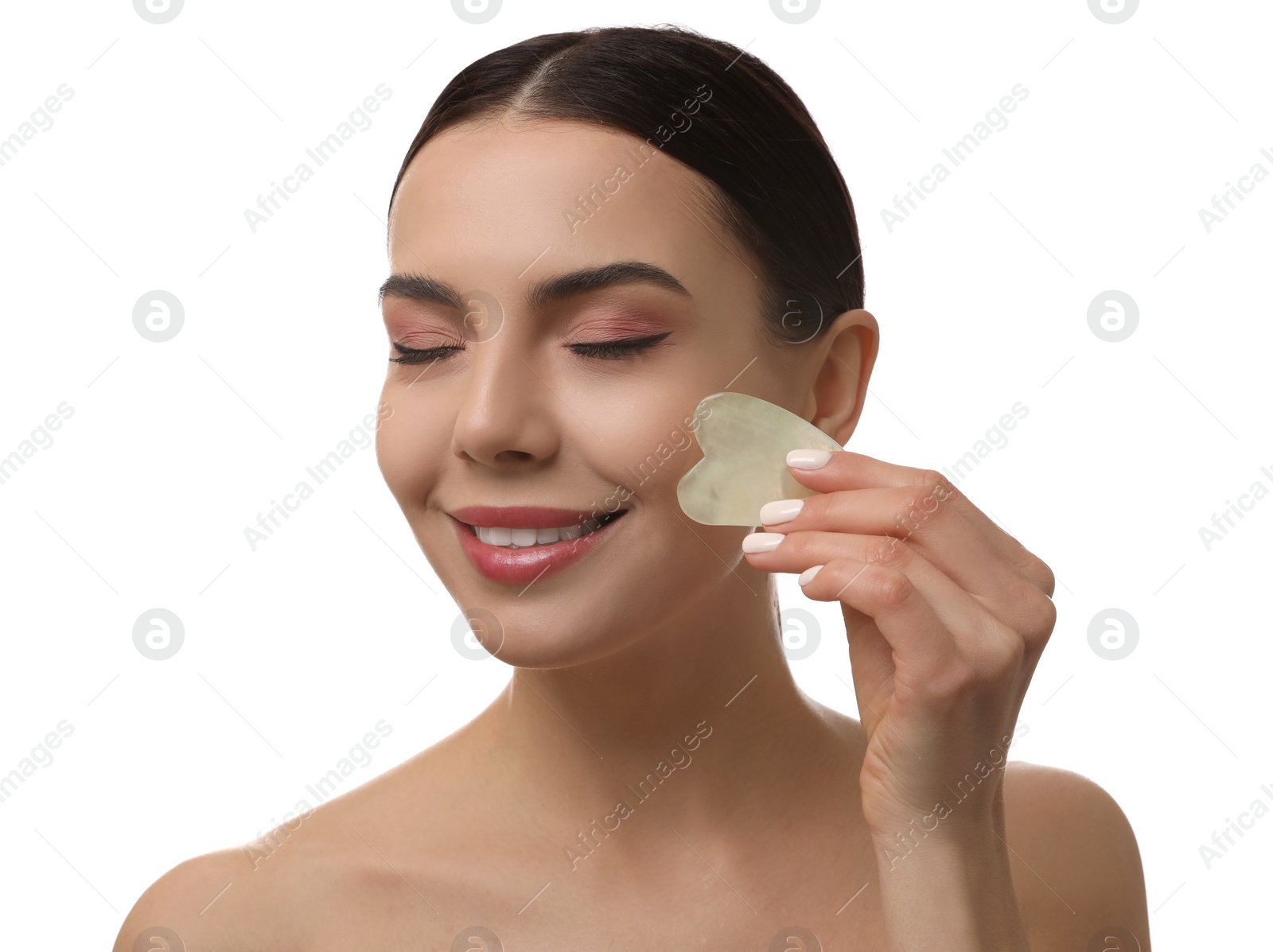 Photo of Beautiful young woman doing facial massage with gua sha tool on white background