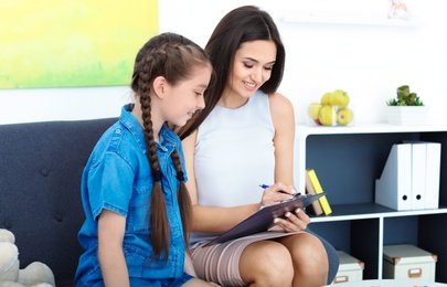 Child psychologist working with little girl in office