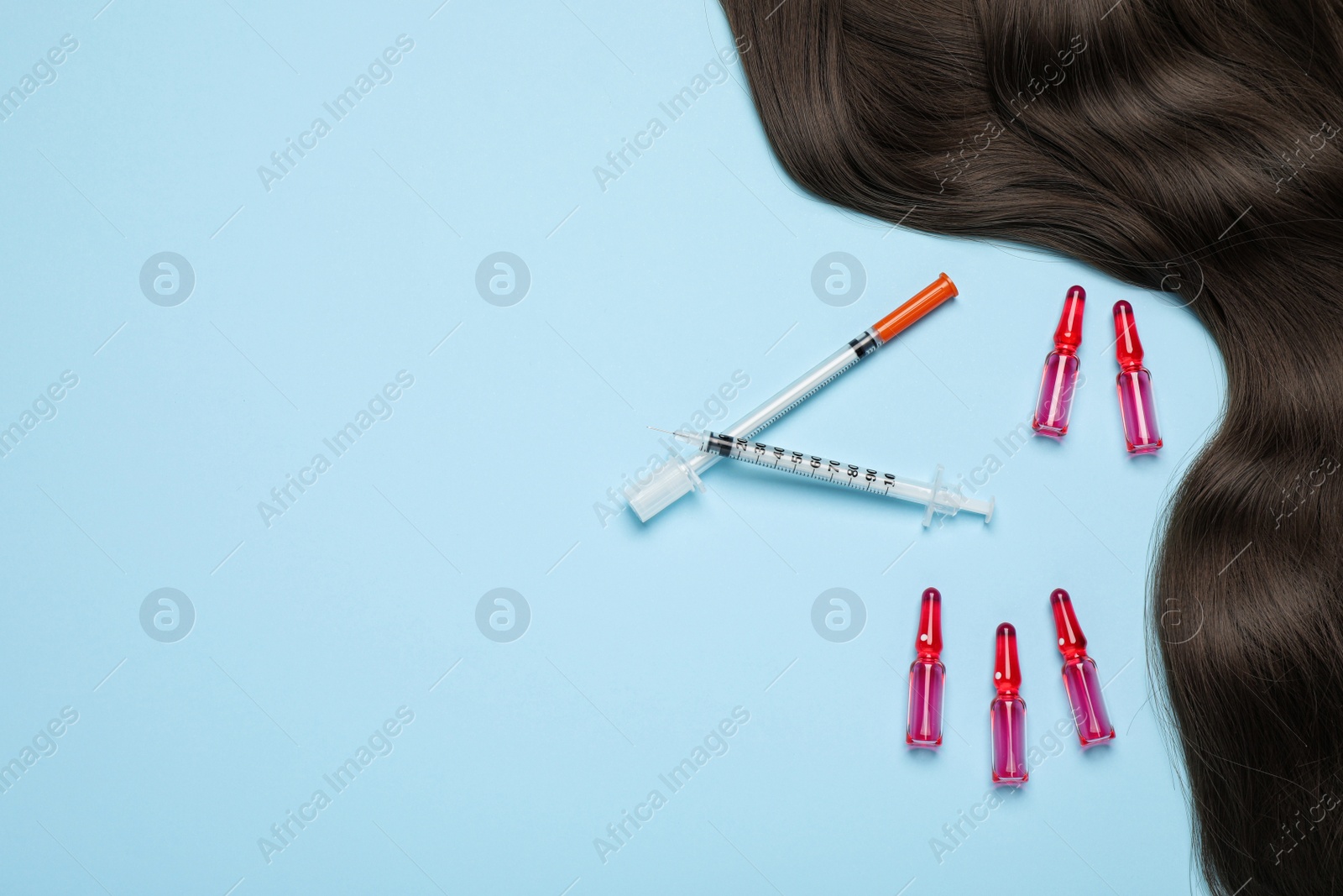Photo of Hair lock, ampoules and syringes on light blue background, flat lay. Space for text