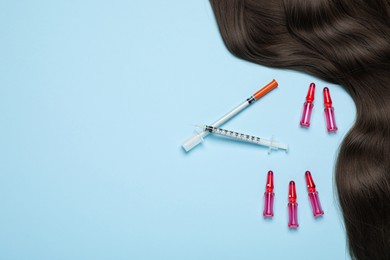 Hair lock, ampoules and syringes on light blue background, flat lay. Space for text