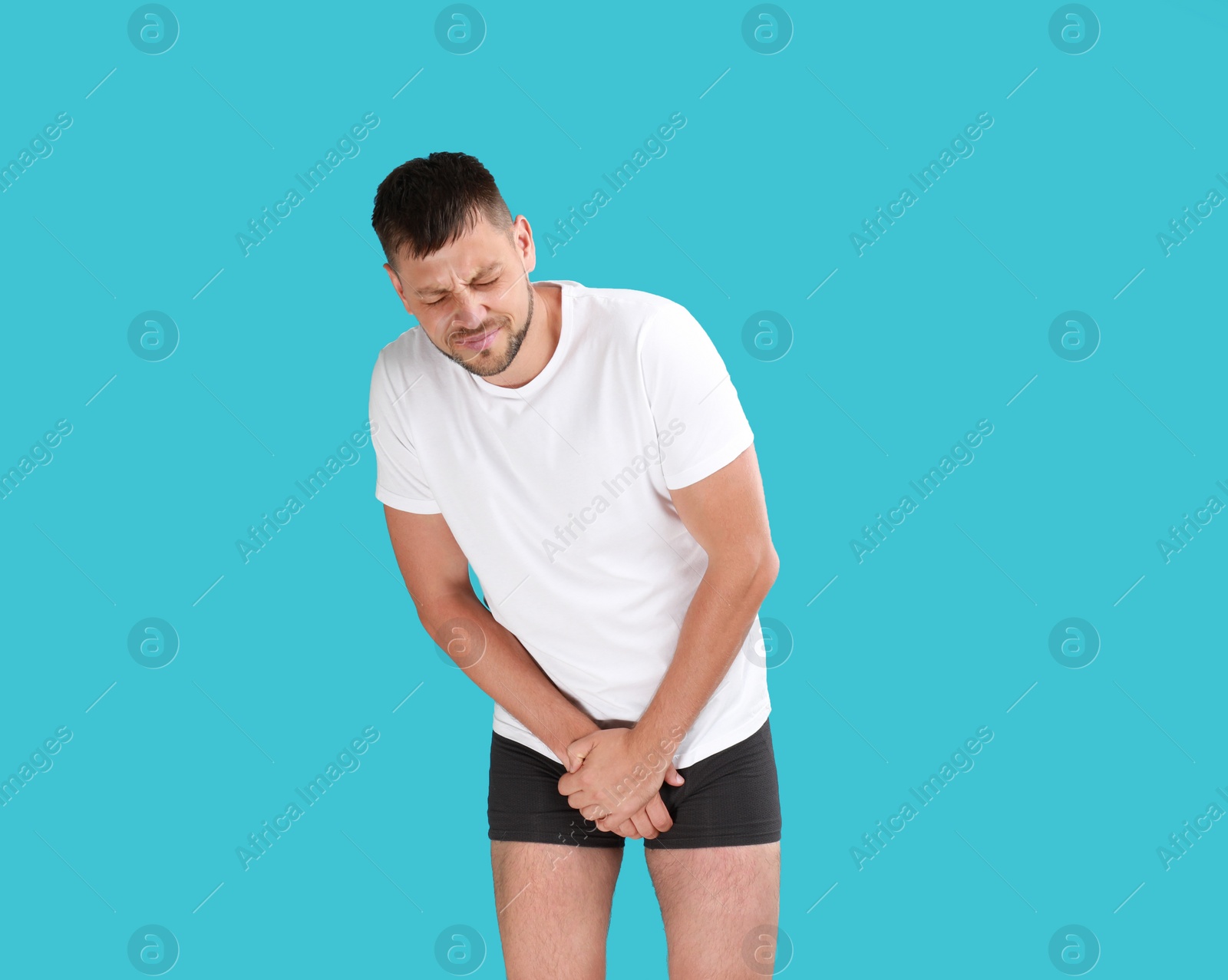 Photo of Man suffering from pain on turquoise background. Urology problems