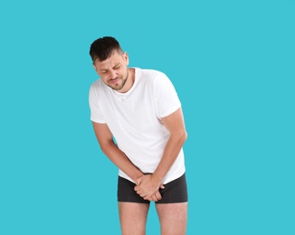 Photo of Man suffering from pain on turquoise background. Urology problems