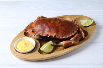 Delicious boiled crab served with lime and sauce on white wooden table