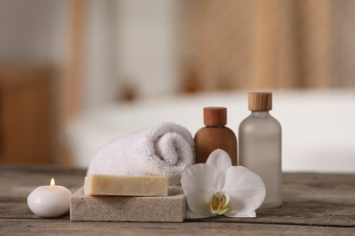 Photo of Composition with spa products and beautiful flower on wooden table against blurred background