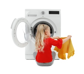 Cute little girl taking laundry out of washing machine on white background