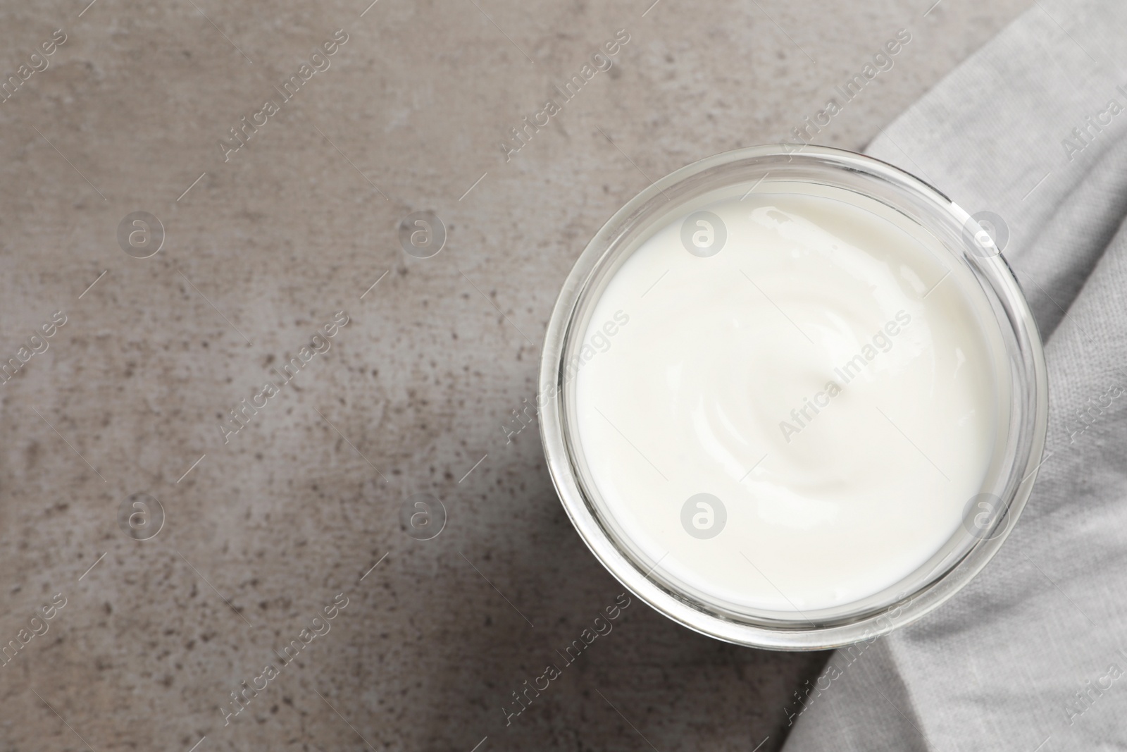 Photo of Jar with delicious organic yogurt on grey table, top view. Space for text